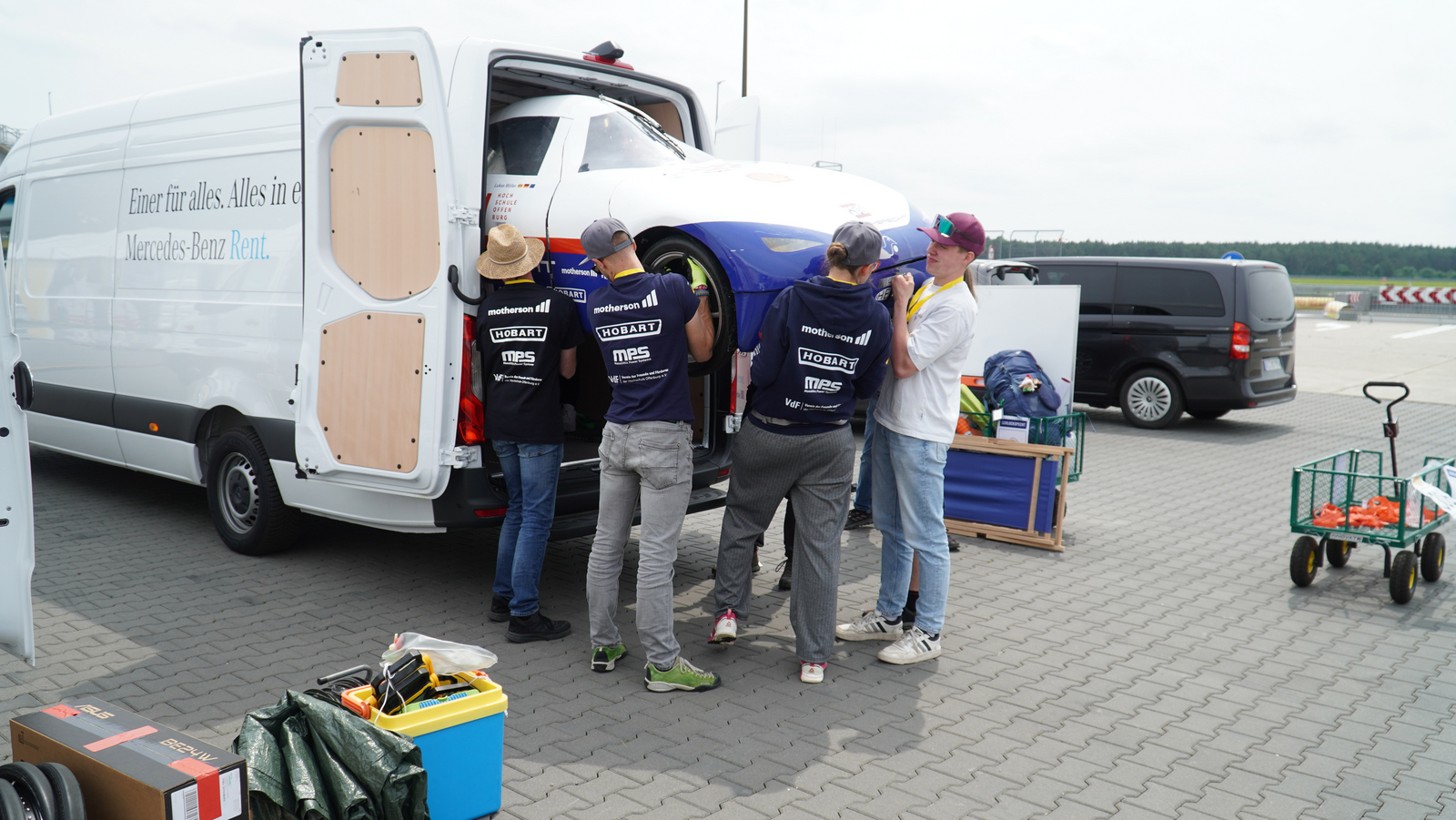 Junge Leute heben zusammen ein Auot aus eine Sprinter