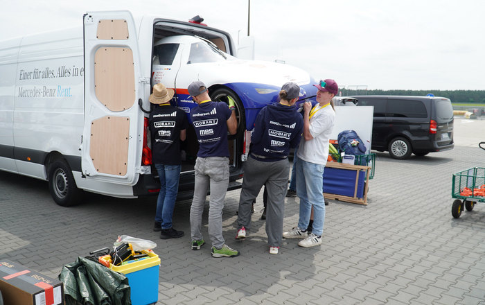 Junge Leute heben zusammen ein Auot aus eine Sprinter
